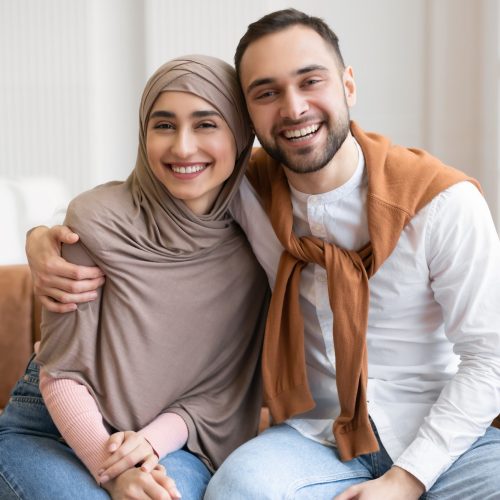 joyful-muslim-spouses-smiling-hugging-sitting-on-sofa-at-home.jpg